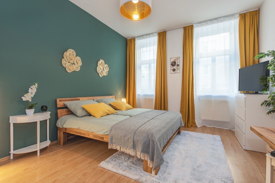 Helles Schlafzimmer mit gelben Vorhängen und gemachtem Bett